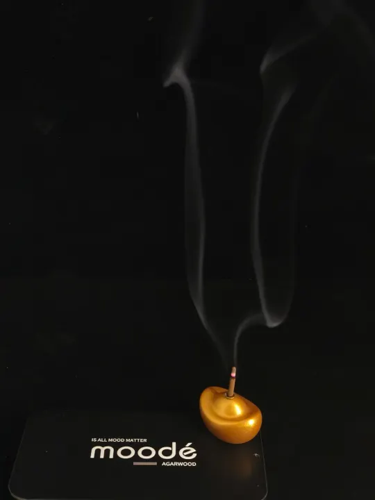 Incense smoke rising from a gold ingot holder